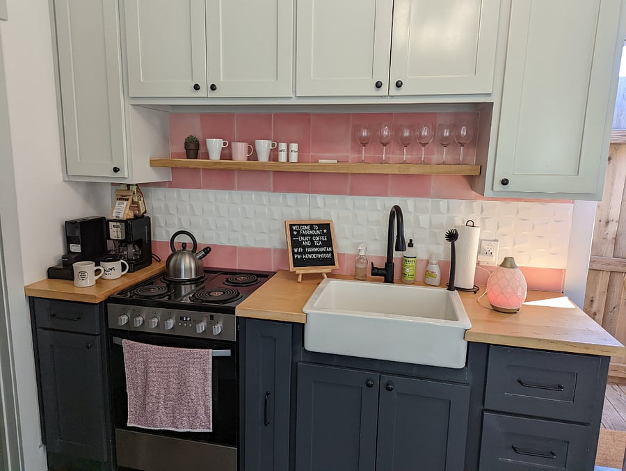 Kitchen area, showing sink, stove, coffee, cabinets, and some of the glassware.