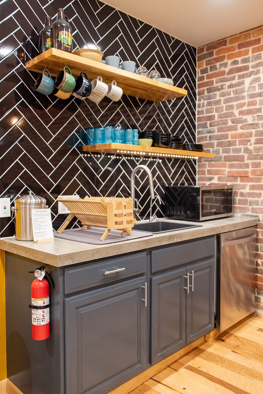 Kitchen sink with floating shelves holding dishware, microwave, and drying rack