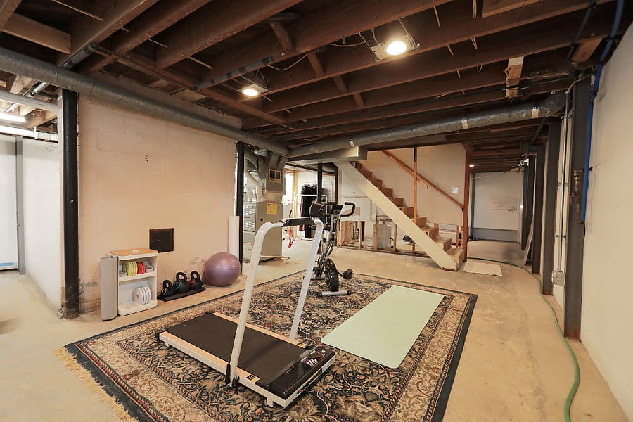 Mini gym has treadmill, exercise bike, yoga mat, kettle bells, and hand weights