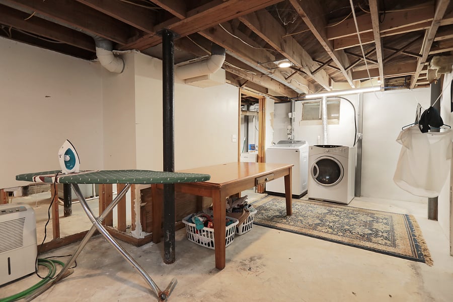 Laundry area with iron, ironing board, laundry sink, and folding table.