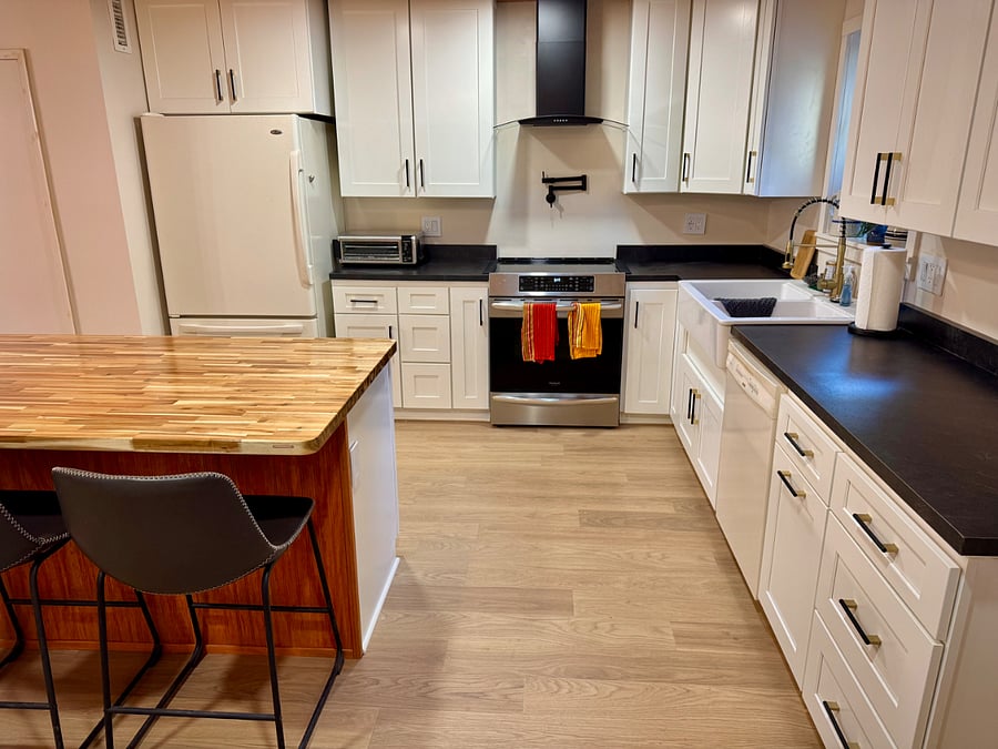 A four burner induction range and oven and many modern appliances make cooking a culinary feast fun and easy in this large, open kitchen.