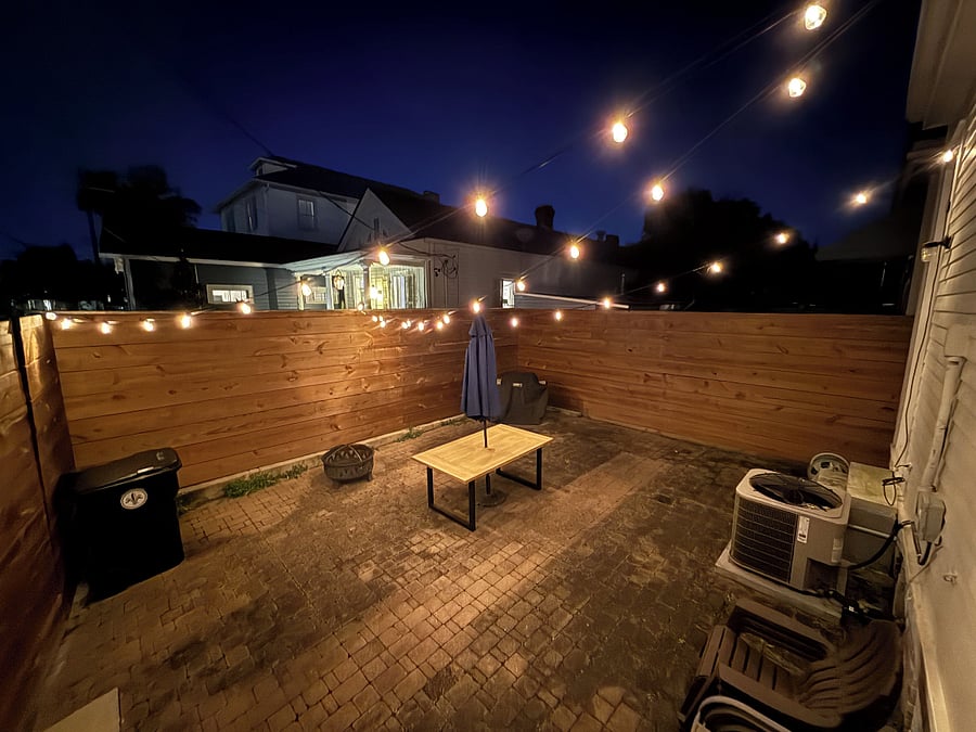 nice back patio with grill, patio furniture and string lights
