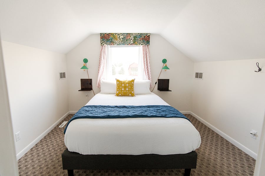 Bedroom 2 is a cozy dormer-style room with a queen bed and is located upstairs. Cheerful mixed prints and pops of colors make the upstairs bedrooms extra enjoyable.
