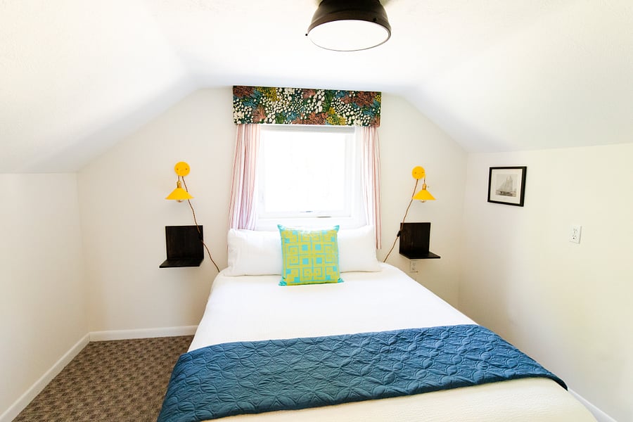 Bedroom 3 is a cozy dormer-style room with a queen bed and is located upstairs. Cheerful mixed prints and pops of colors make the upstairs bedrooms extra enjoyable.