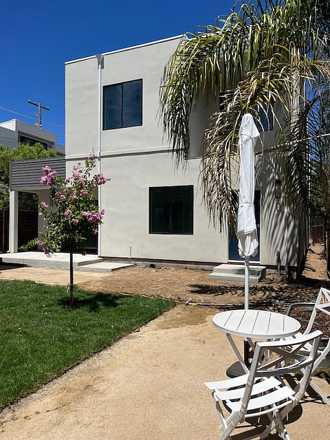 View of the two story duplex from the shared yard. The private outdoor patio is located in the left corner of the photo.