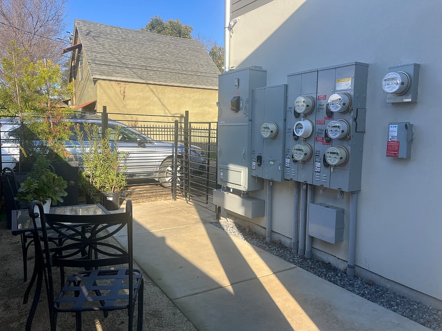 The electric meter and panels for the property are located on the building within the gated front patio.