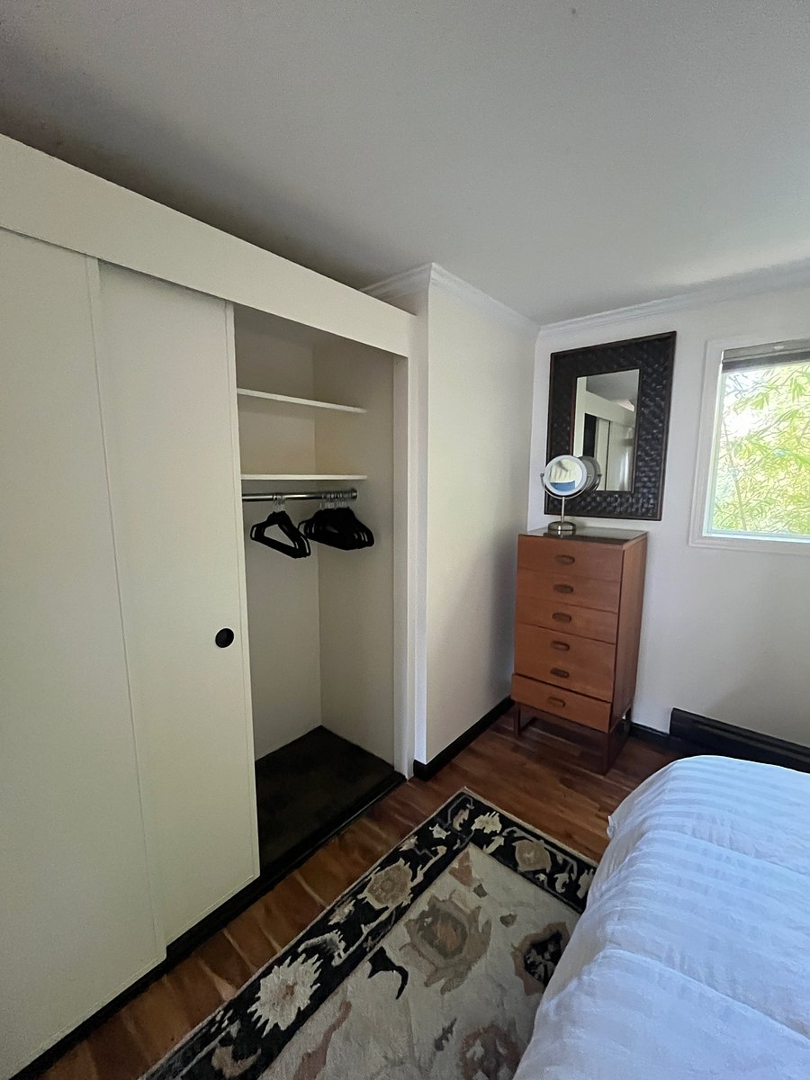 Bedroom dresser and closet with sliding doors.