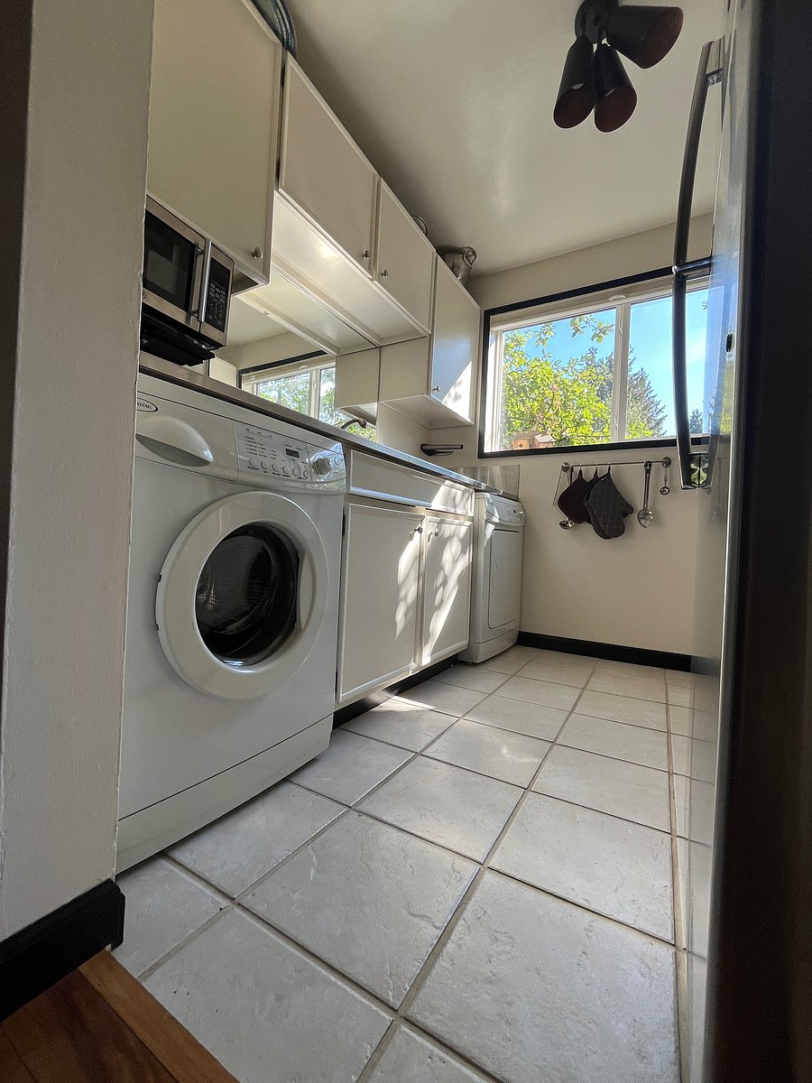 Kitchen with giant windows facing the 
West. Kitchen features microwave, stove, oven, full fridge, sink, washer/dryer and cabinets with essentials.