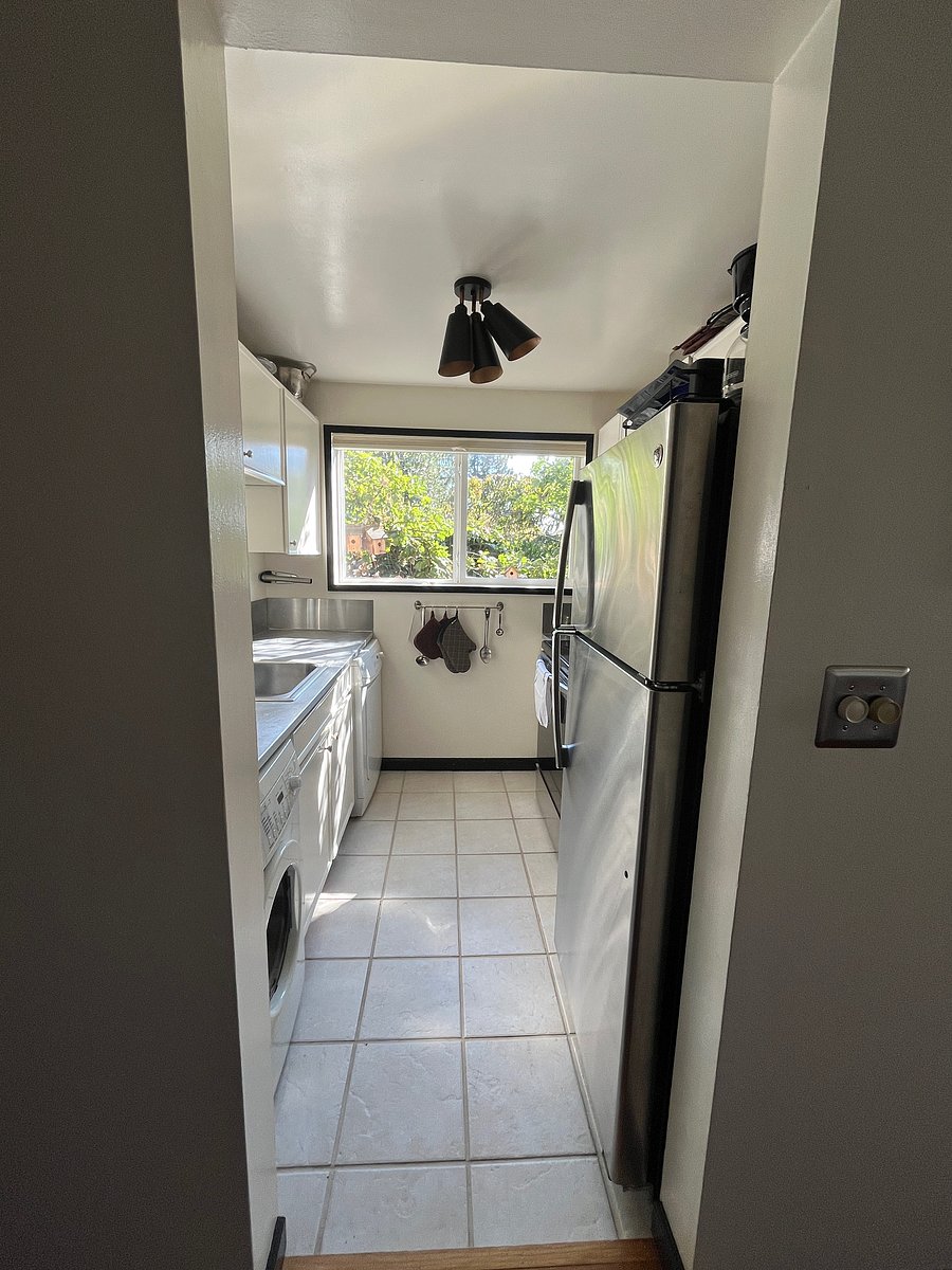 Kitchen with giant windows facing the 
West. Kitchen features microwave, stove, oven, full fridge, sink, washer/dryer and cabinets with essentials.