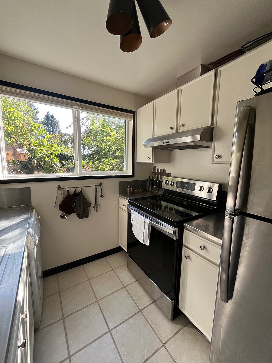 Kitchen with giant windows facing the 
West. Kitchen features microwave, stove, oven, full fridge, sink, washer/dryer and cabinets with essentials.