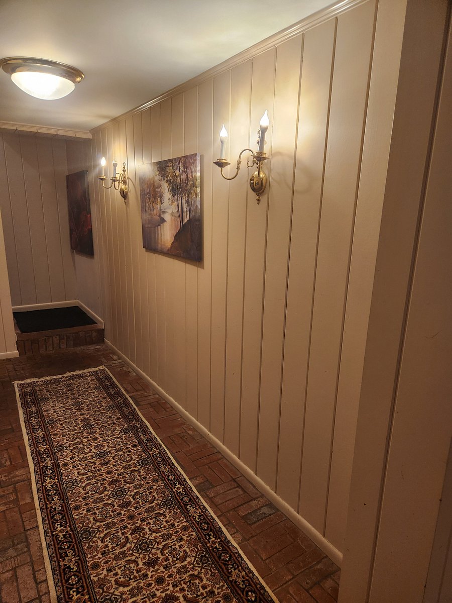 Hallway to primary bedroom with brand new sized bed and plush mattress, full bathroom with bench seat shower.