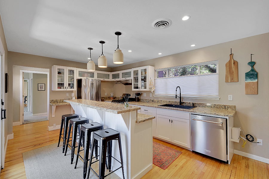 Well-appointed kitchen with bar seating that includes a gas stove, oven, fridge, microwave (in pantry), and dishwasher