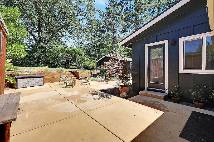 Backyard/patio seen after entering through side gate. Glass-paned door accesses the third bathroom.