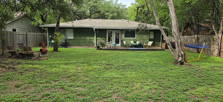 There is a large backyard with a variety of seating and entertainment areas.