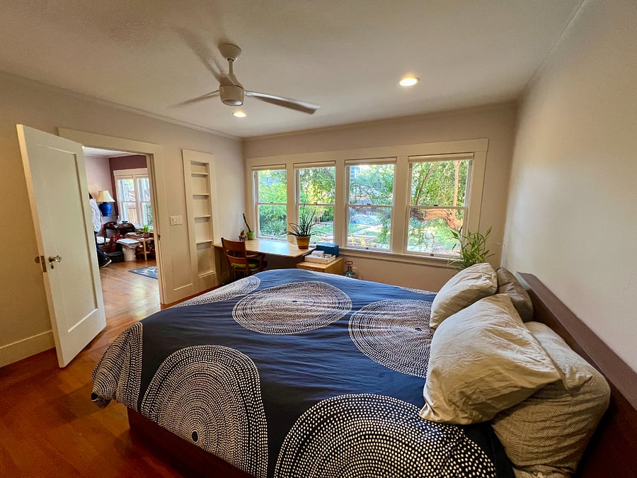 A large set of windows along the wall of the primary bedroom allow warm, filtered light in through the trees. Full length window shades can quickly be pulled down to enhance privacy or keep out the morning sun.