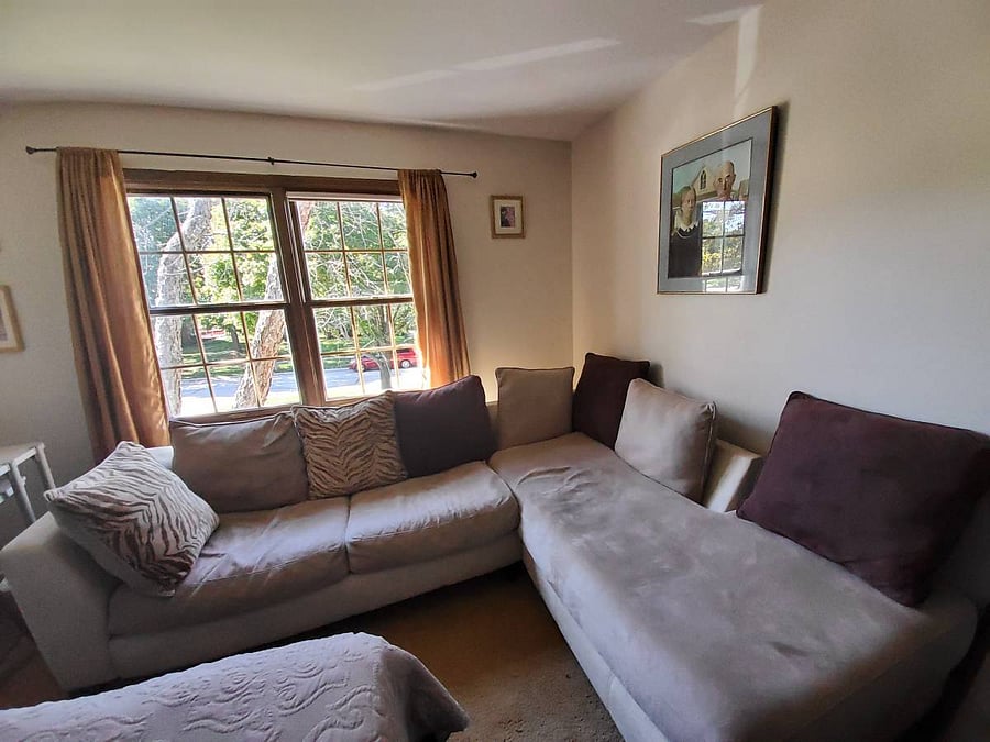 Comfortable L-shaped sofa by a large window, ideal for relaxing after work.