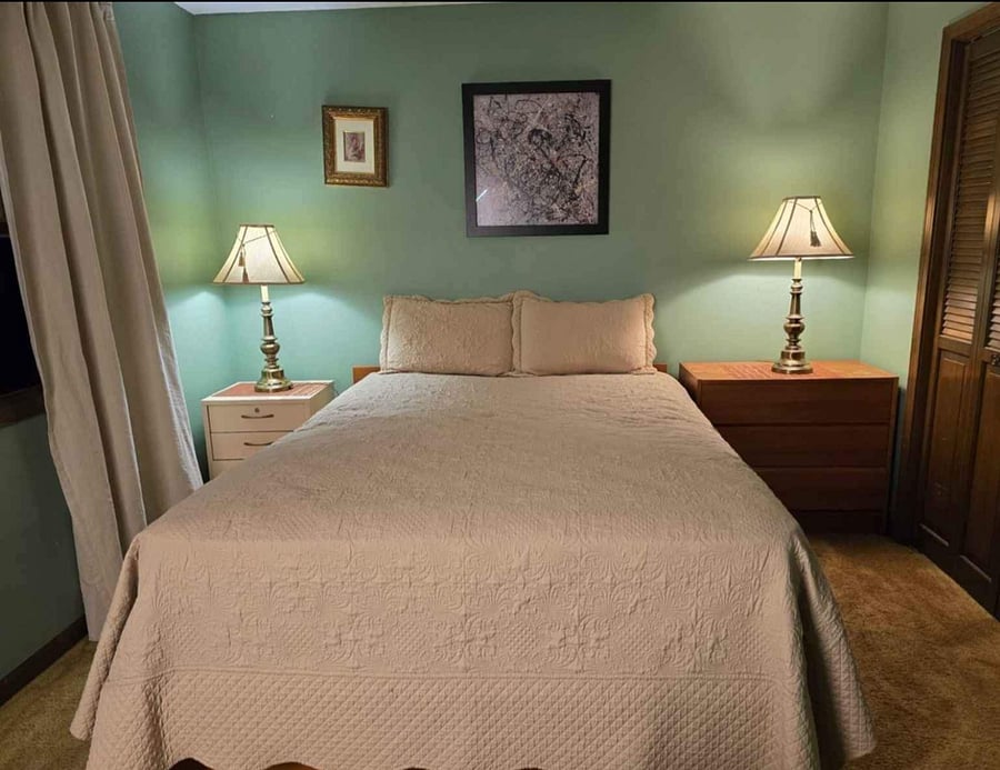 Comfortable queen-size bed with two bedside lamps and simple dcor, perfect for relaxing and a restful sleep.