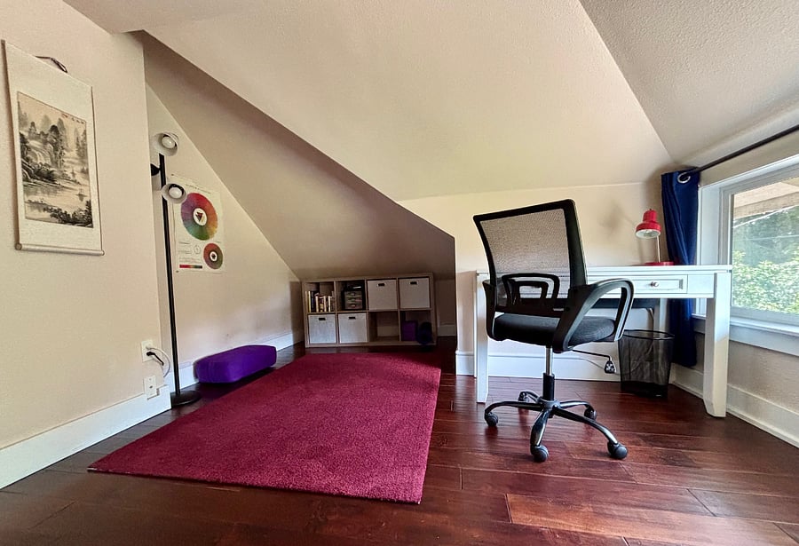 Private office nook with workspace, high-speed internet, bookshelf, books, yoga mat, and bolster.