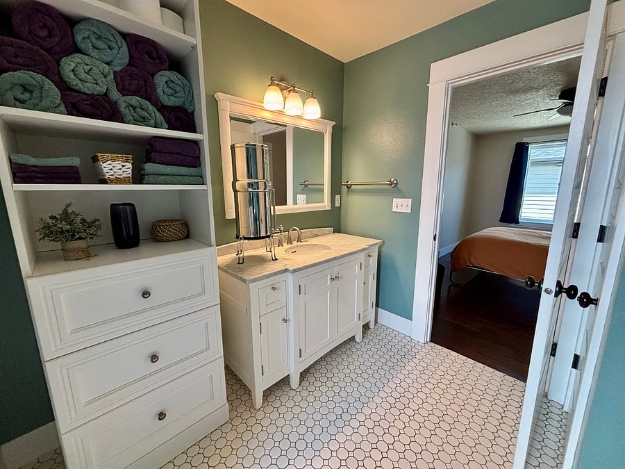 Private bathroom with full vanity, linen storage, Berkey water filter, and Bluetooth speaker.