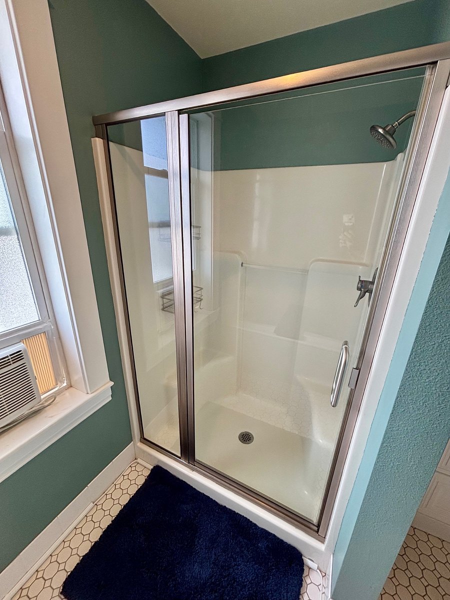 Private bathroom with shower and AC window unit.
