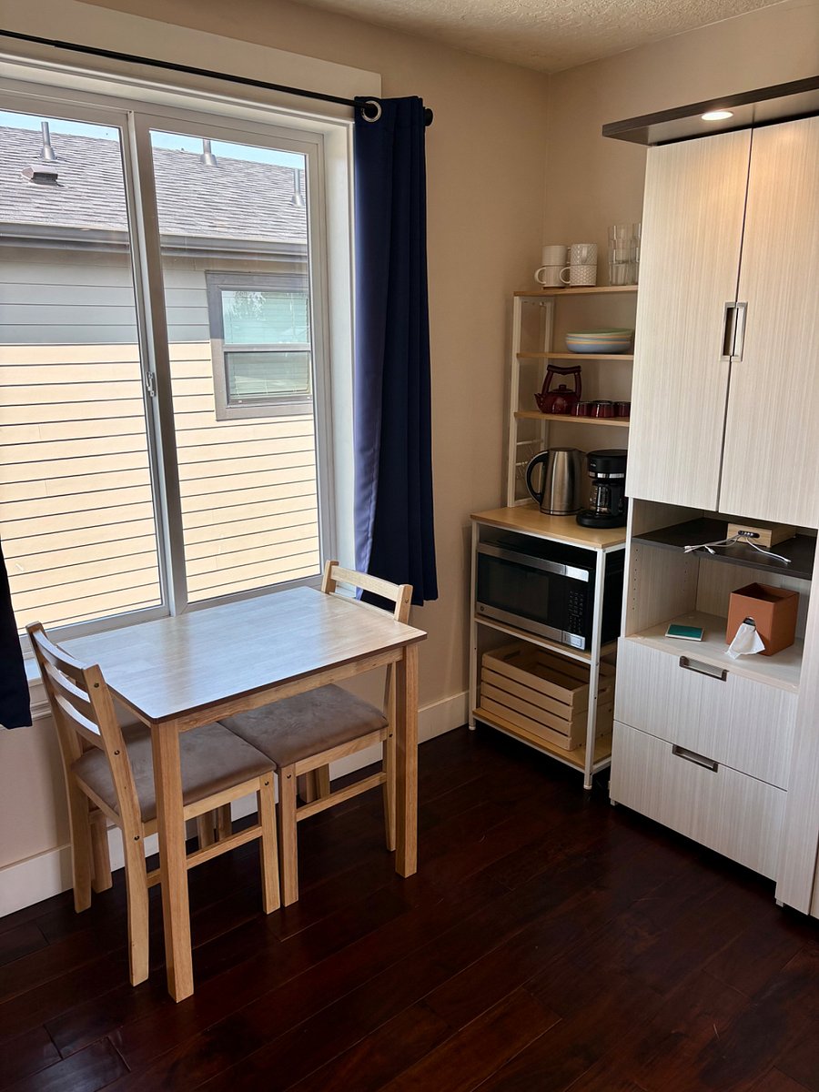 Dining nook with table and two chairs, plus a coffee bar with microwave, coffee maker, kettle, dishes, glasses, and mugs.