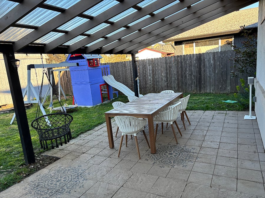 Shared fully fenced backyard with a covered patio, outdoor dining space, and Sonos speaker.