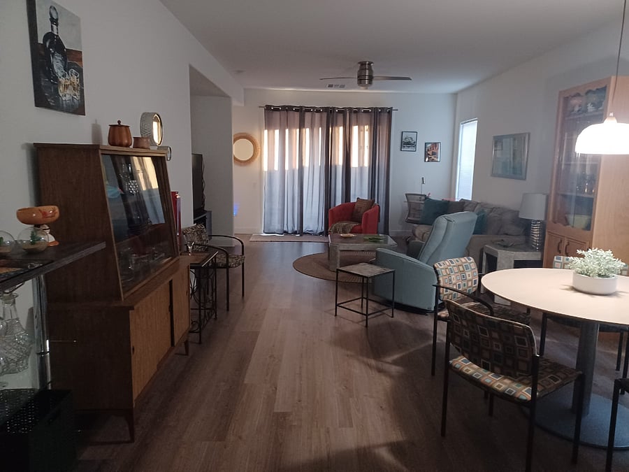 The house has an open floorplan decorated with a mid century modern flair. Living space has a ceiling fan.