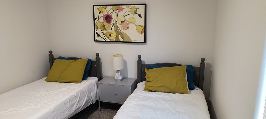 Third bedroom has two twin beds, two night stands a ceiling fan and closet.