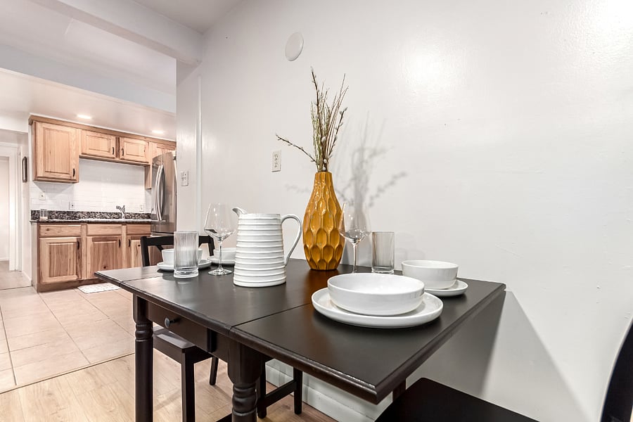 Chic dining setup- stylish table with elegant white plates, bowls, and glass drink ware. A cozy space for meals, morning coffee, or working remotely.