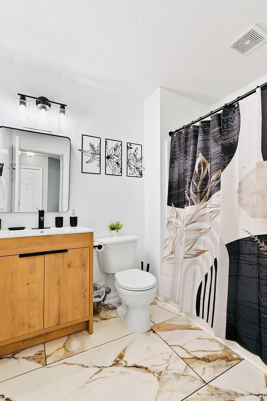 A newly renovated bathroom exudes modern elegance w sleek & minimalist design. Features pristine large marble tile flooring contrasted by matte black fixtures for a bold, contemporary touch. Providing ambiance & accessories for a spa feel. (Shared)