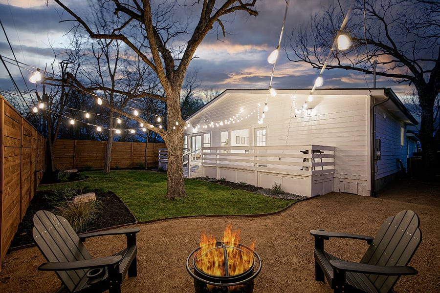 The back yard includes seating on the deck and a fire pit under a string of lights. Perfect for a cup of coffee in the morning, or a cold drink after a day at work