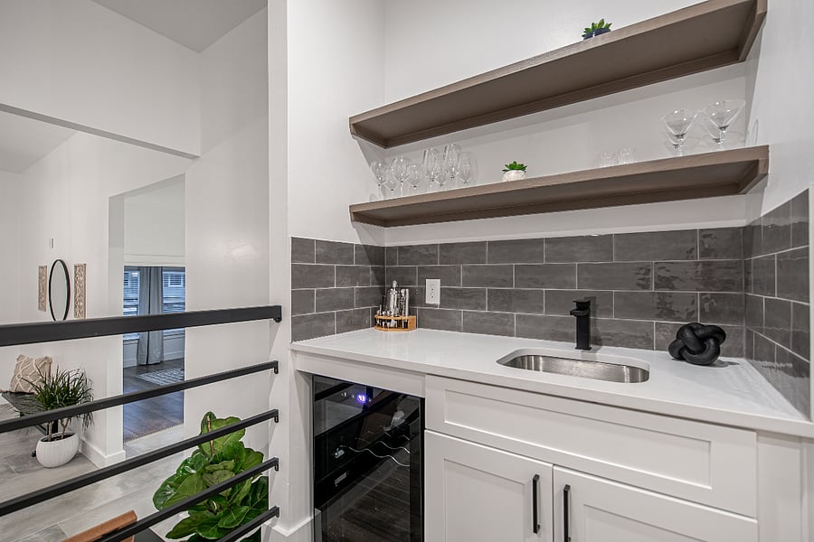 Bar area includes built in beverage fridge, bar tools, and plenty of wine and martini glasses