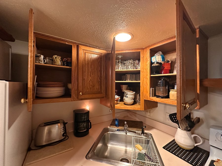 kitchen- stocked with plates, glasses, sliverware, cooking utensils, pots and pans