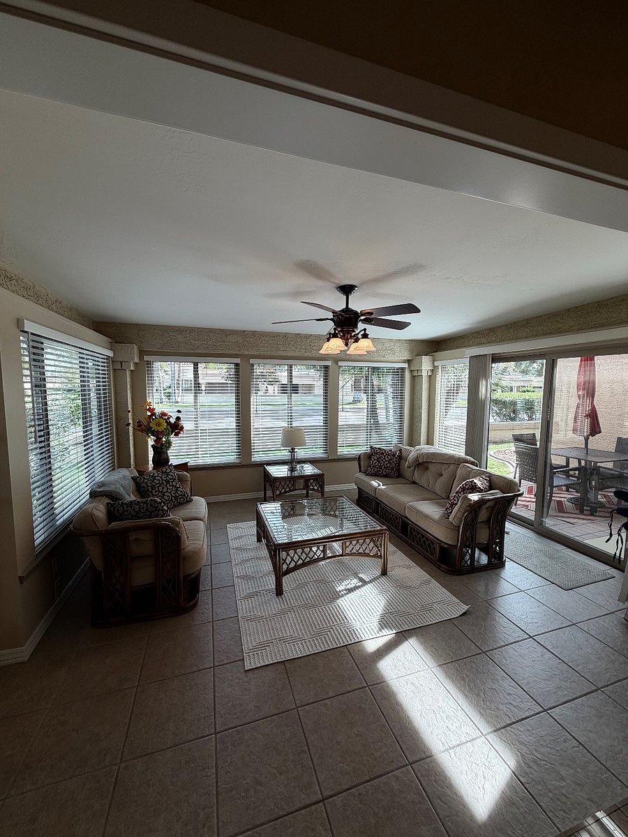 ENCLOSED SUN ROOM LEADING TO SIDE PATIO WITH DINING AREA AND WEBER GAS GRILL.