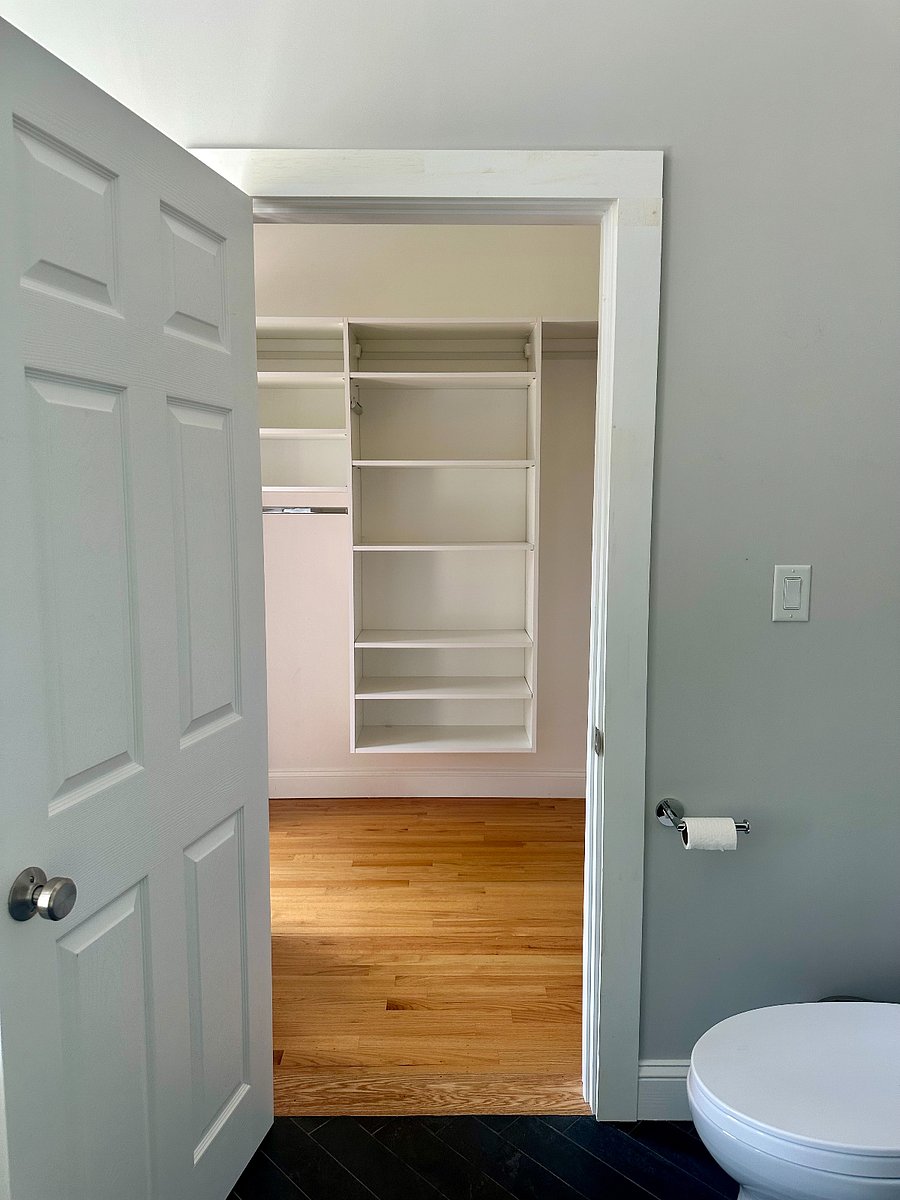 Primary closet with full-length mirror and three walls of shelving