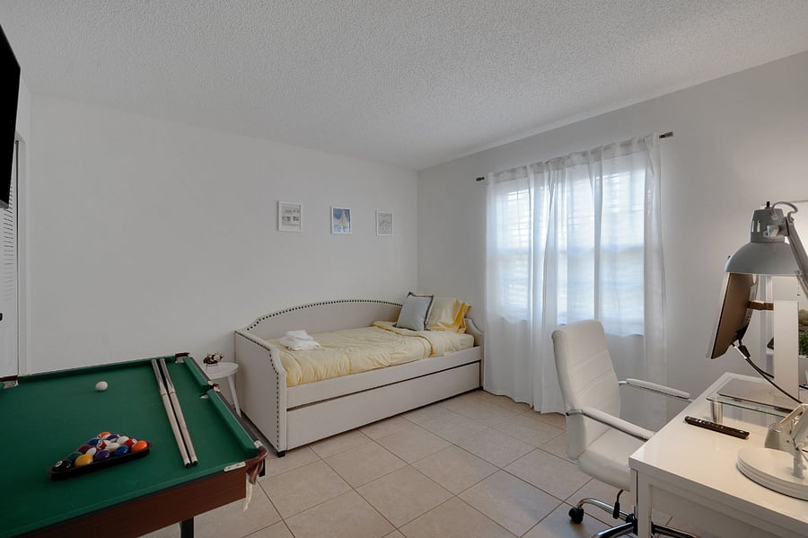 Versatile third bedroom with twin daybed + trundle, 43 smart TV, desk with monitor and speaker, foldable 55 pool table, yoga mat, board games, and optional queen air mattress. Ideal for rest, remote work, or play.