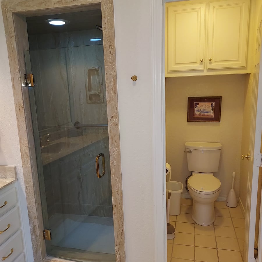 Primary bathroom walk-in shower with ledge, toilet with privacy door