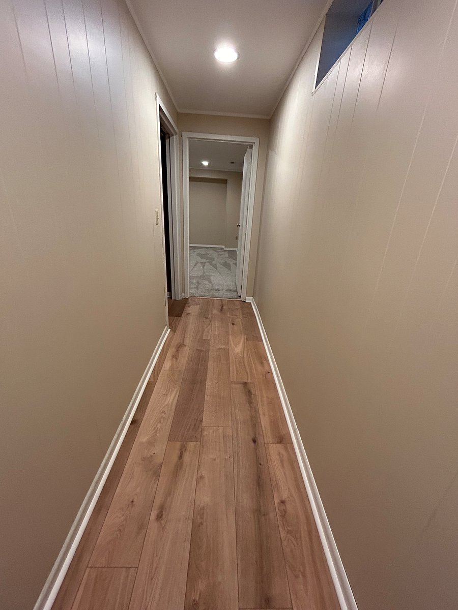 Hallway at bottom of stairwell that leads straight into bedroom and to the left is the connector room that leads to the bathroom, laundry, and off room.