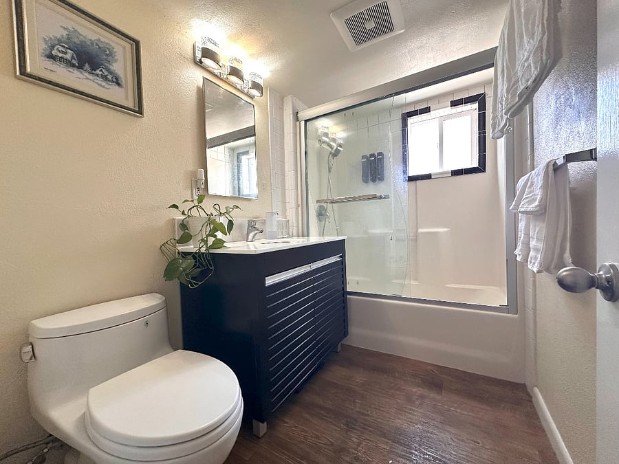 The suite includes a full private bathroom with a shower/tub, toilet, and vanity sink, stocked with fresh towels and basic toiletries for your convenience.