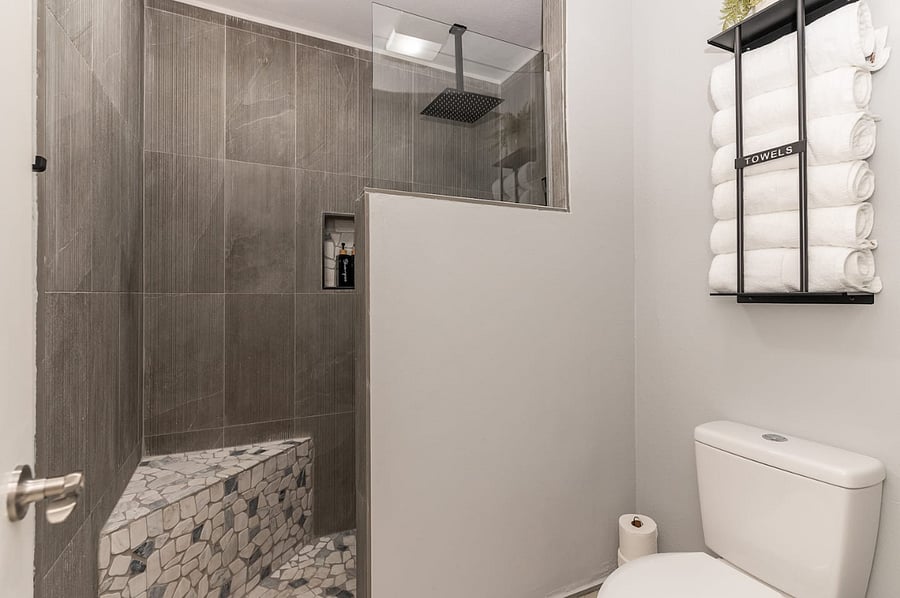 -Walk-in rainfall shower with custom tile bench and stone flooring for a luxe, spa-like retreat. -Fresh towels and hotel-style essentials provided for ultimate comfort. -Thoughtfully designed with convenience, style, and cleanliness in mind.
