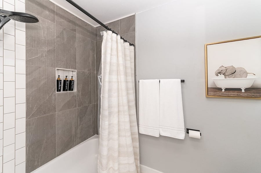 Modern tile shower with built-in niches and provided toiletries for a hotel-style experience.