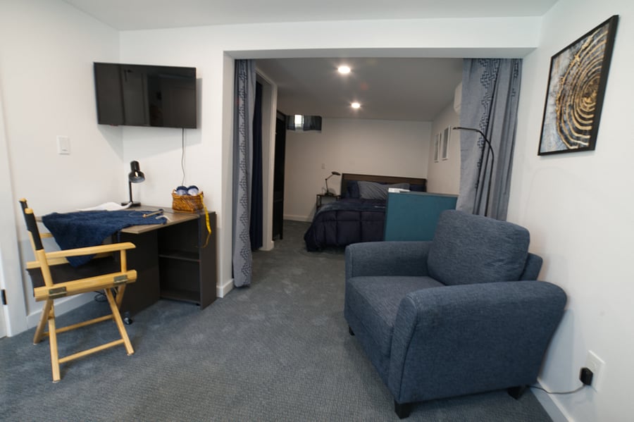 Your Queen bedroom beyond parlor with privacy curtains, closet wardrobe and chest of drawers, TV and drop leaf table.