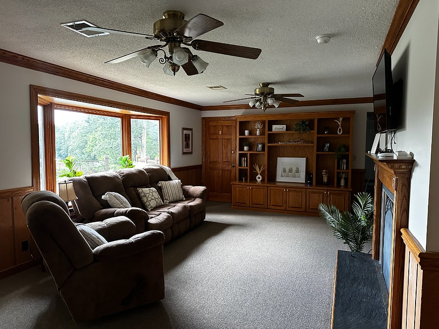 Den displaying the bay window overlooking the covered (closed) pool and lower part of the property where the farm is located