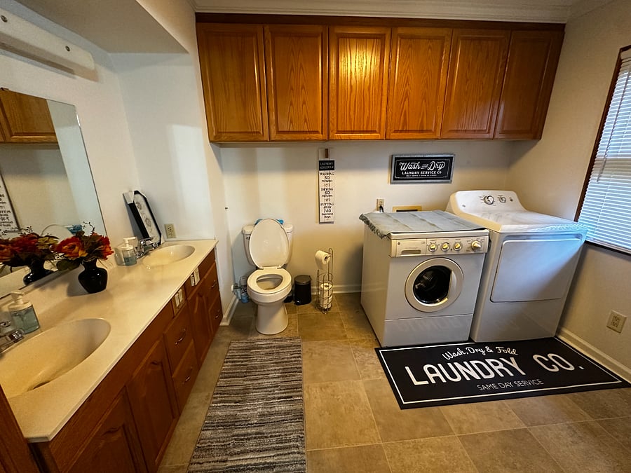 The spacious laundry room with a half bath and double vanity sinks is located off the eating area of the kitchen.  There is a full size ironing board with iron here as well. 