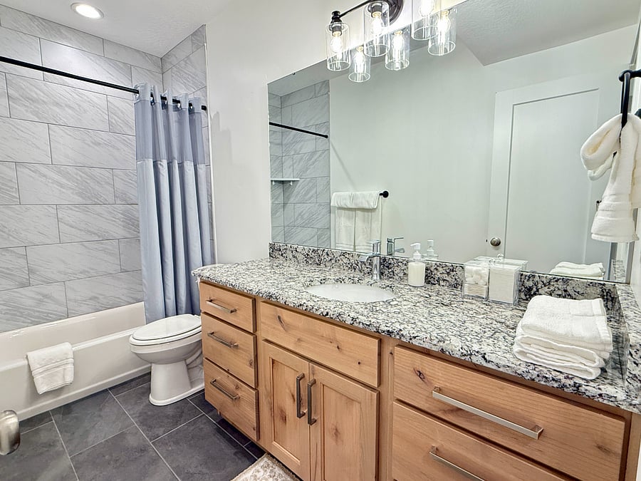Stylish bathroom with a modern vanity, marble countertops, a spacious tub/shower combo, and soft water for a luxurious stay