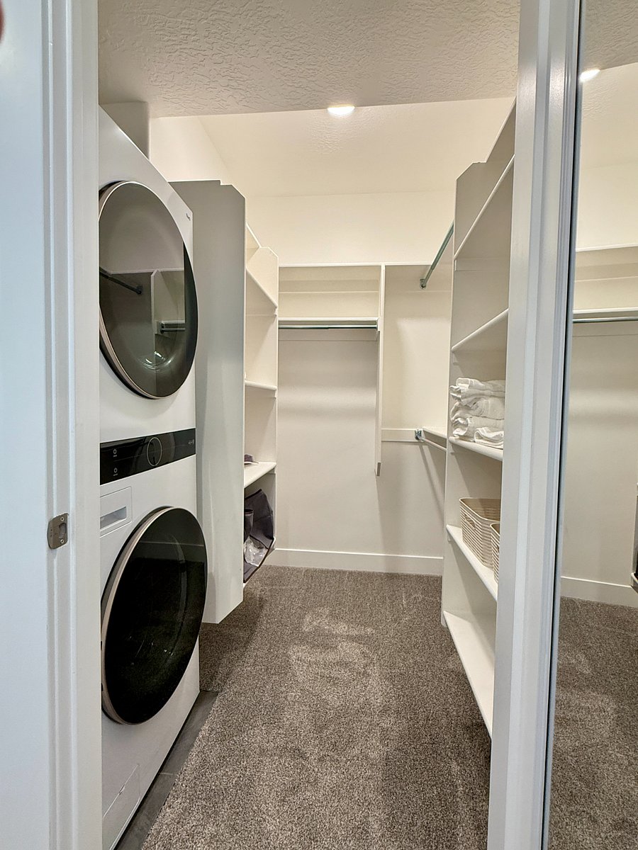 Convenient walk-in bedroom closet with ample shelving, hanging space, and a stackable washer/dryer