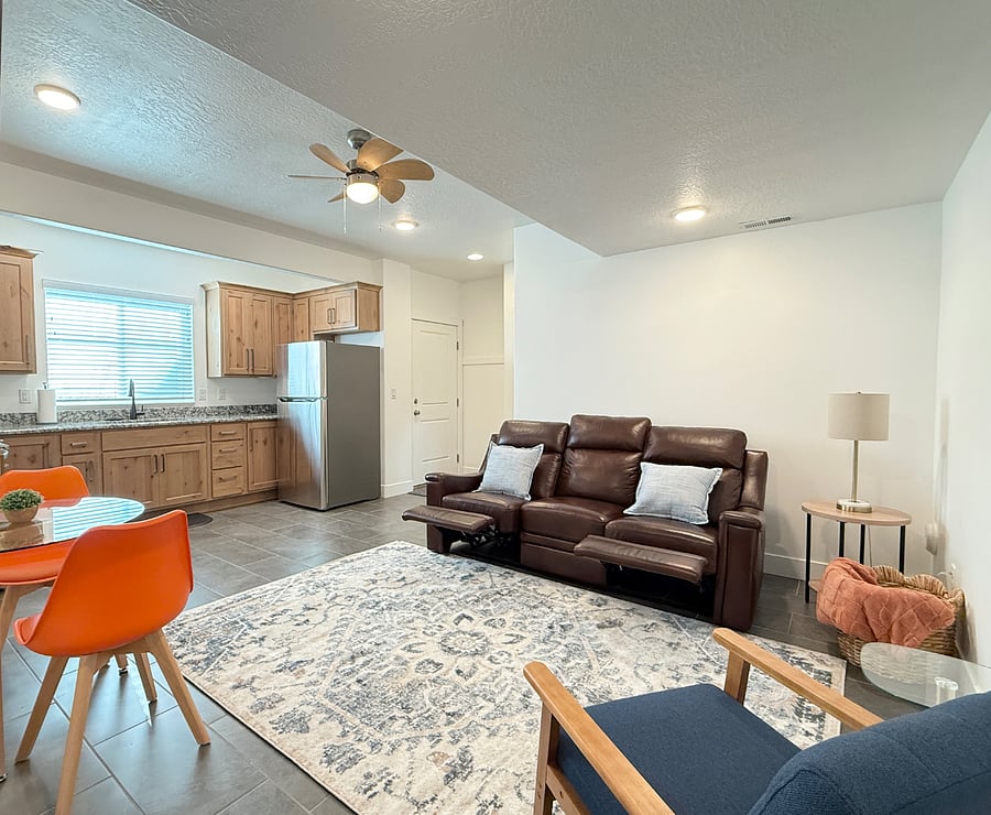 Open living area with a modern kitchen, comfortable leather reclining sofa, and dining space