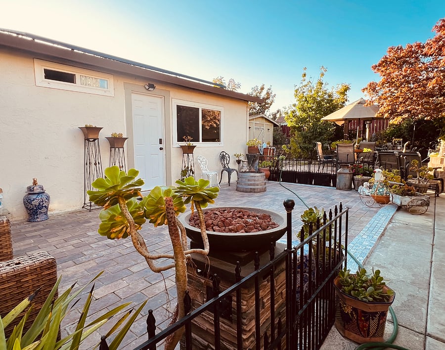 The living space extends to a beautifully maintained patio, surrounded by lush, vibrant greenery: a peaceful escape right outside your door.