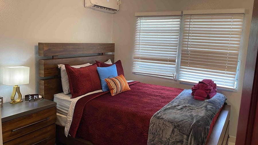 The second bedroom has a queen bed for two guests with Fire TV, fan, extra storage, seating, and cool AC