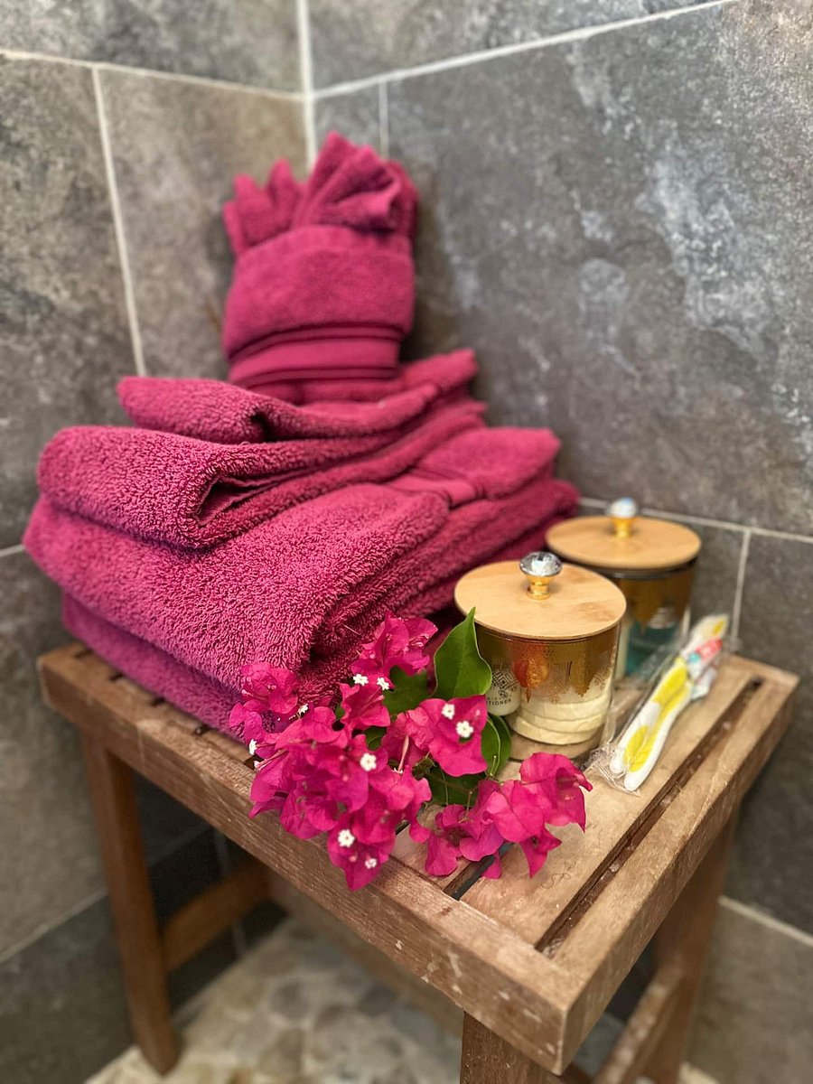 Welcome to your serene bathroom experience with shower bench, peekaboo outdoor window view, toiletries, towels, soothing shower floor with stones, earthy slate tiles, and rainfall shower head.